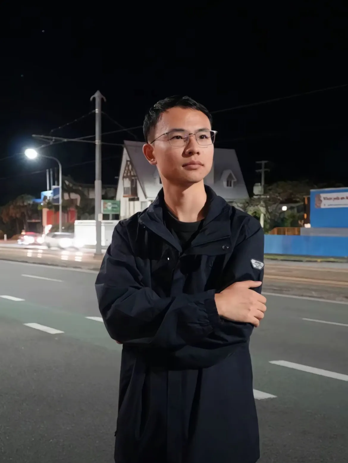 这套生活主张的一位奠基者的照片，戴着眼镜、身穿深色外套，站在夜晚的街道旁